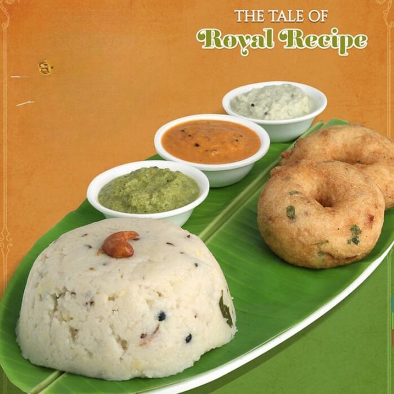 Indian breakfast platter with upma, vada, and three chutneys on a banana leaf.