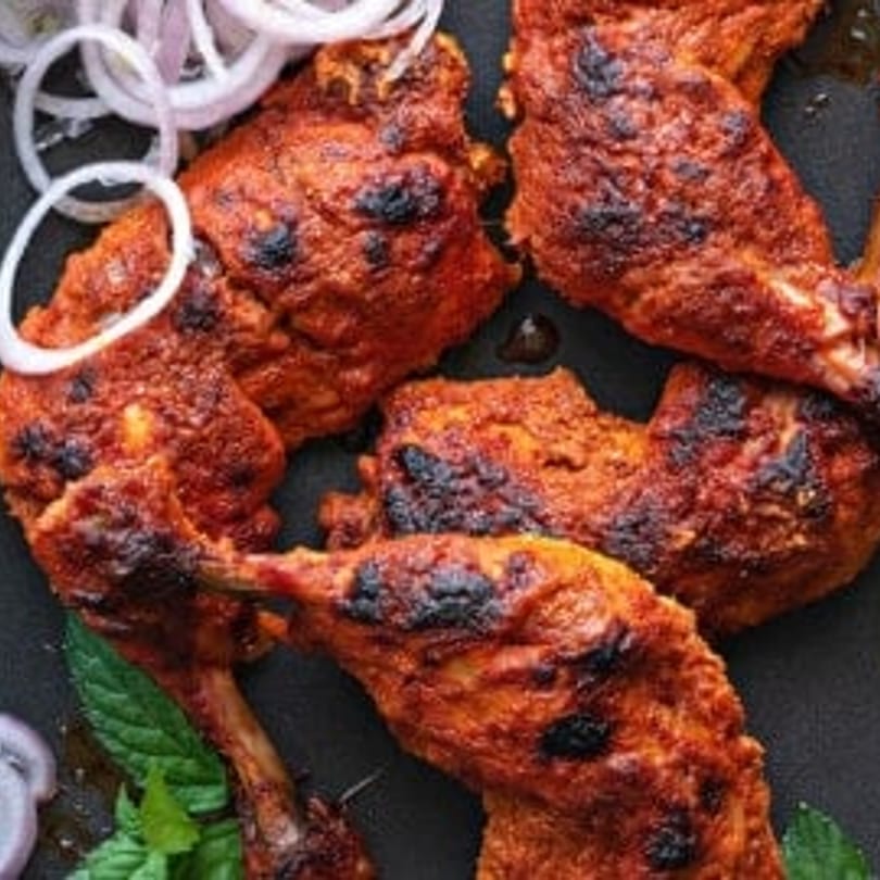 Close-up of Bawarchi Biryanis' Indian chicken wings, garnished with mint and sliced onions.
