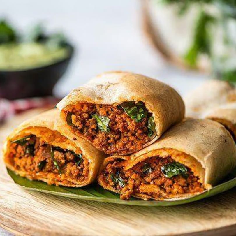 Three Indian keema parathas, filled with spiced ground meat and herbs, on a banana leaf.
